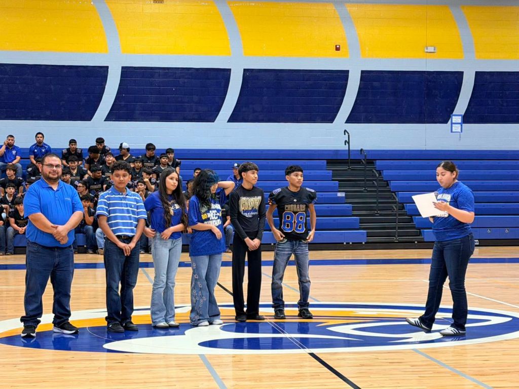 The Santa Maria Cross Country Team stands next to their coach as they are being presented to the audience.